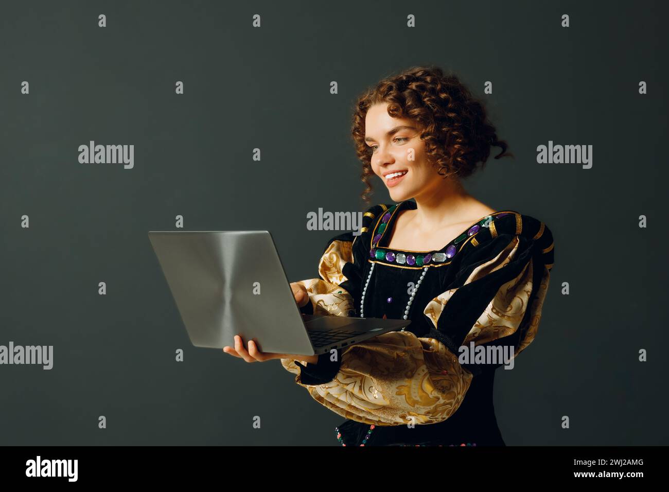 Porträt einer jungen Aristokratin in einem mittelalterlichen Kleid, die am Laptop arbeitet. Stockfoto