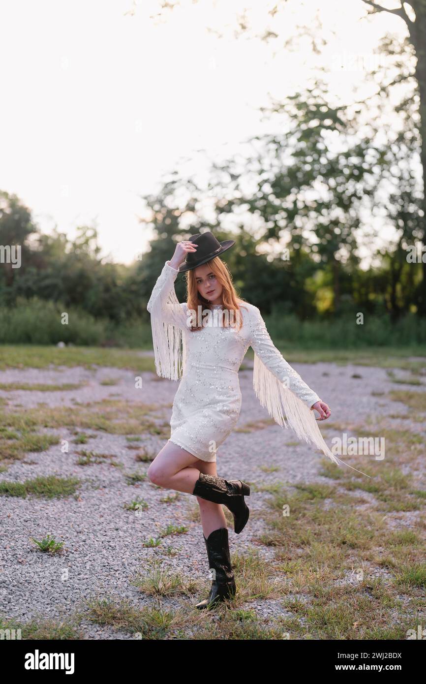 Cowgirl steht auf dem Feld, hüpfend, mit Fransenkleid Stockfoto