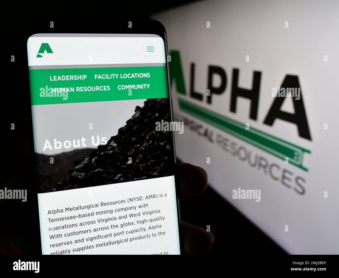 Person, die ein Handy hält, mit Webseite des US-Bergbauunternehmens Alpha Metallurgical Resources Inc. Vor dem Logo. Konzentrieren Sie sich auf die Mitte des Telefondisplays. Stockfoto