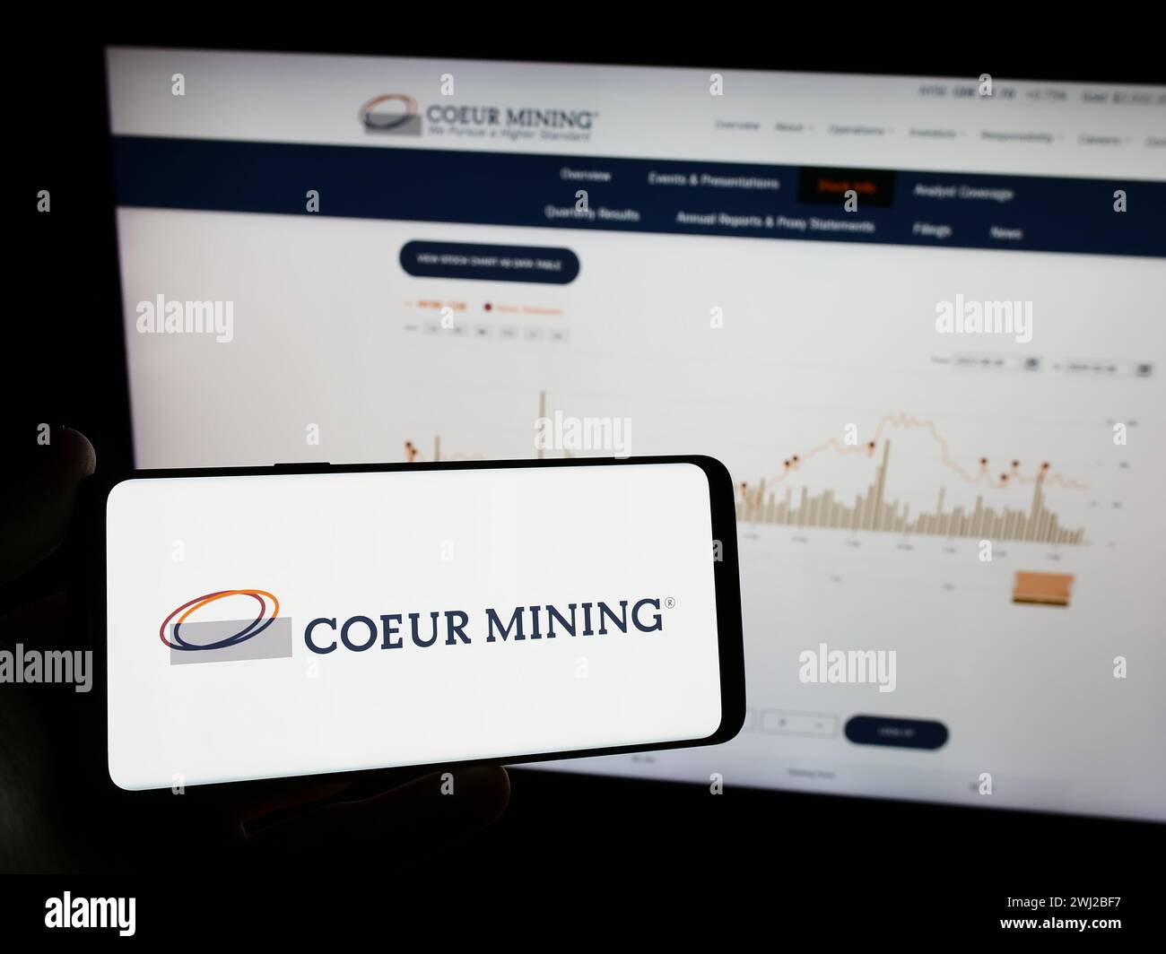Person, die ein Mobiltelefon mit dem Logo des amerikanischen Edelmetallunternehmens Coeur Mining Inc. Vor der Business-Webseite hält. Schwerpunkt auf dem Display des Telefons. Stockfoto