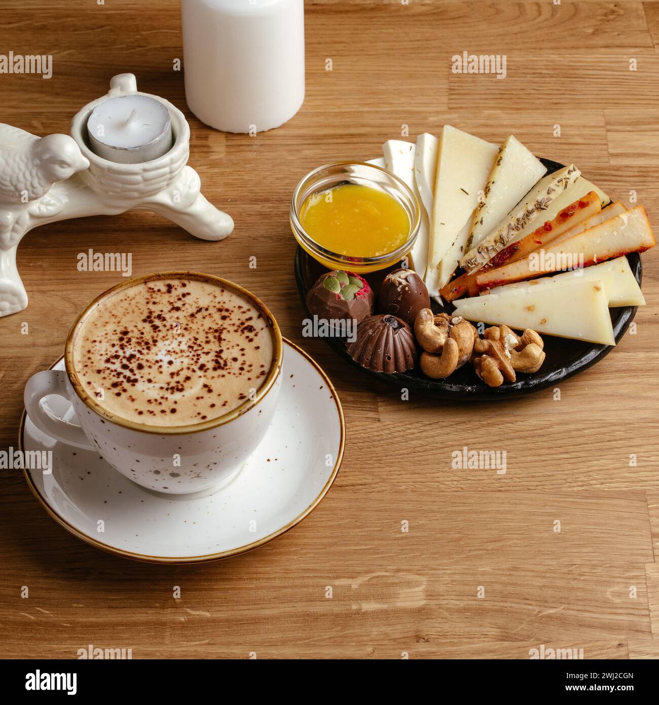 Ziegenkäse, Nüsse und Honig auf einem Teller und Kaffee daneben Stockfoto
