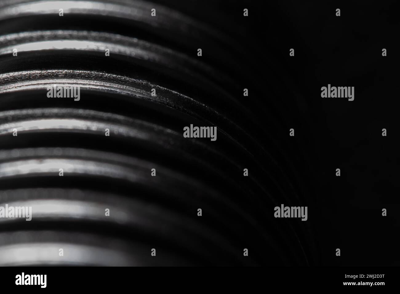Nahaufnahme des Gewindes einer Metallschraube auf schwarzem Hintergrund, strukturiertes Metall, abstraktes Makro Stockfoto