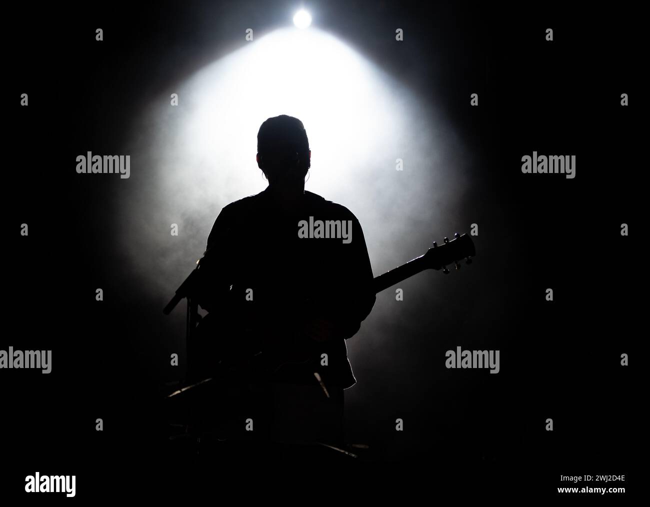 Musiker, der Gitarre spielt, spielt auf der Bühne unter Scheinwerferlicht. Silhouette eines Musikkünstlers und einer Band auf der Bühne Stockfoto