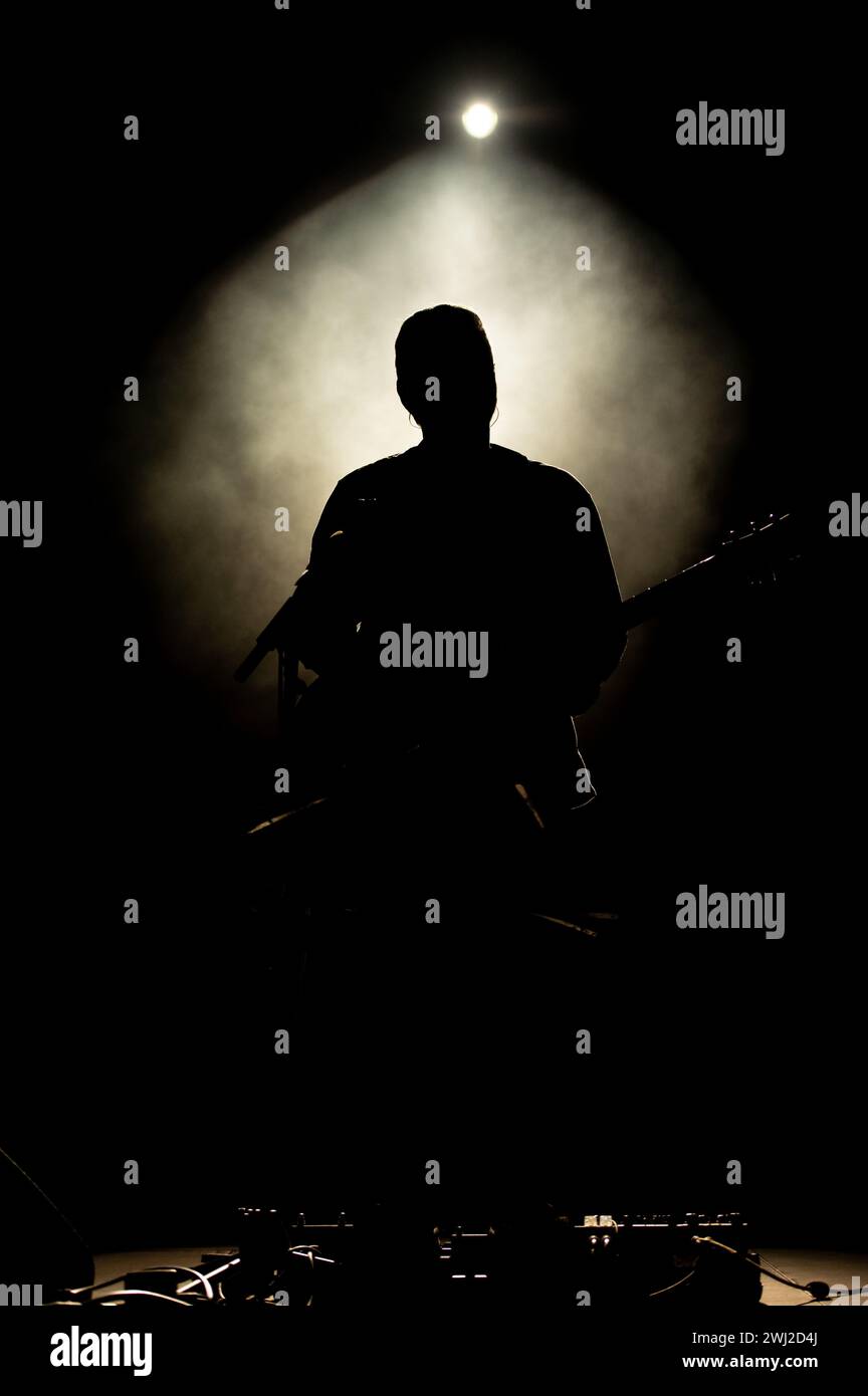 Musiker, der Gitarre spielt, spielt auf der Bühne unter Scheinwerferlicht. Silhouette eines Musikkünstlers und einer Band Stockfoto