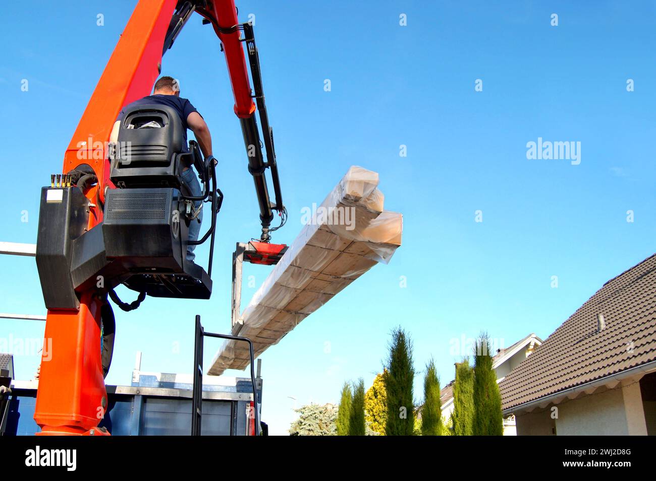 Truck liefert Holzpakete, die für den Bau eines Carports, einer Garage verwendet werden. Kranfahrer Stockfoto