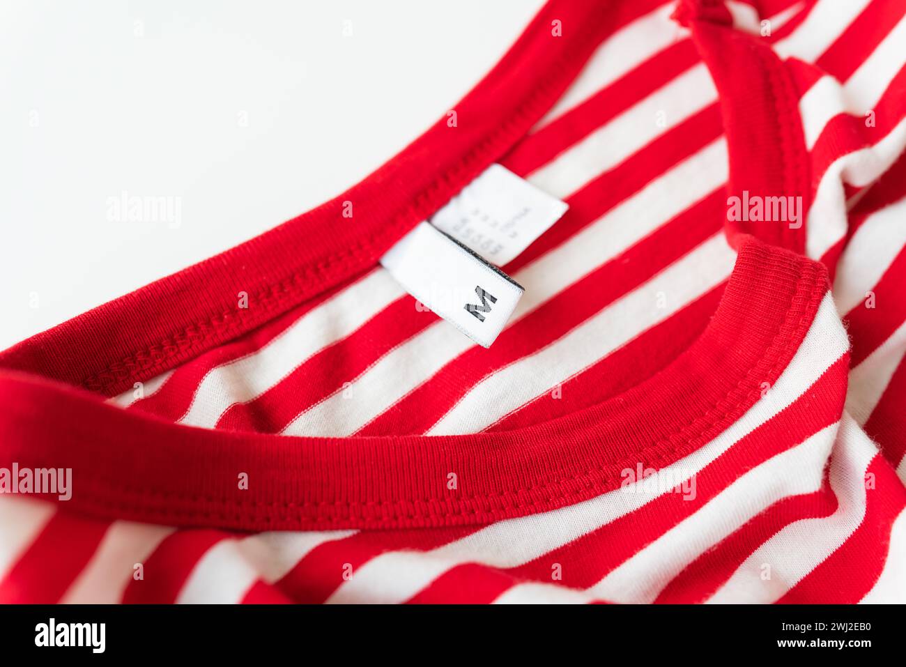 Nahaufnahme eines rot-weiß gestreiften Hemdes mit M-Größe. Weiches Baumwollmaterial, ordentliche Nähte, bequeme Passform Stockfoto