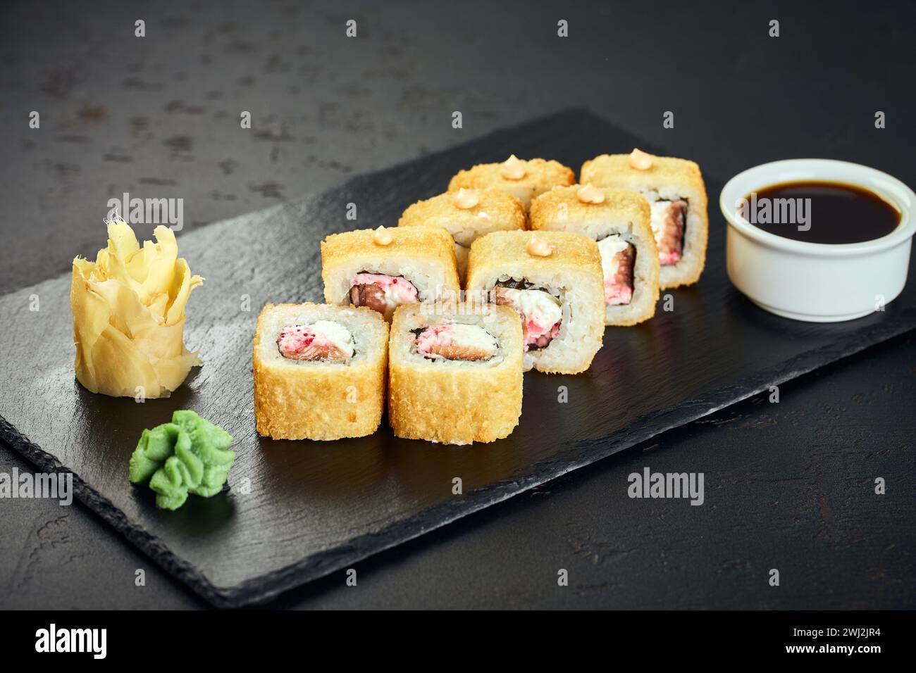 Tempura heiße Sushi-Brötchen mit Lachs auf dunklem Hintergrund. Sushi-Menü. Japanisches Essen. Stockfoto