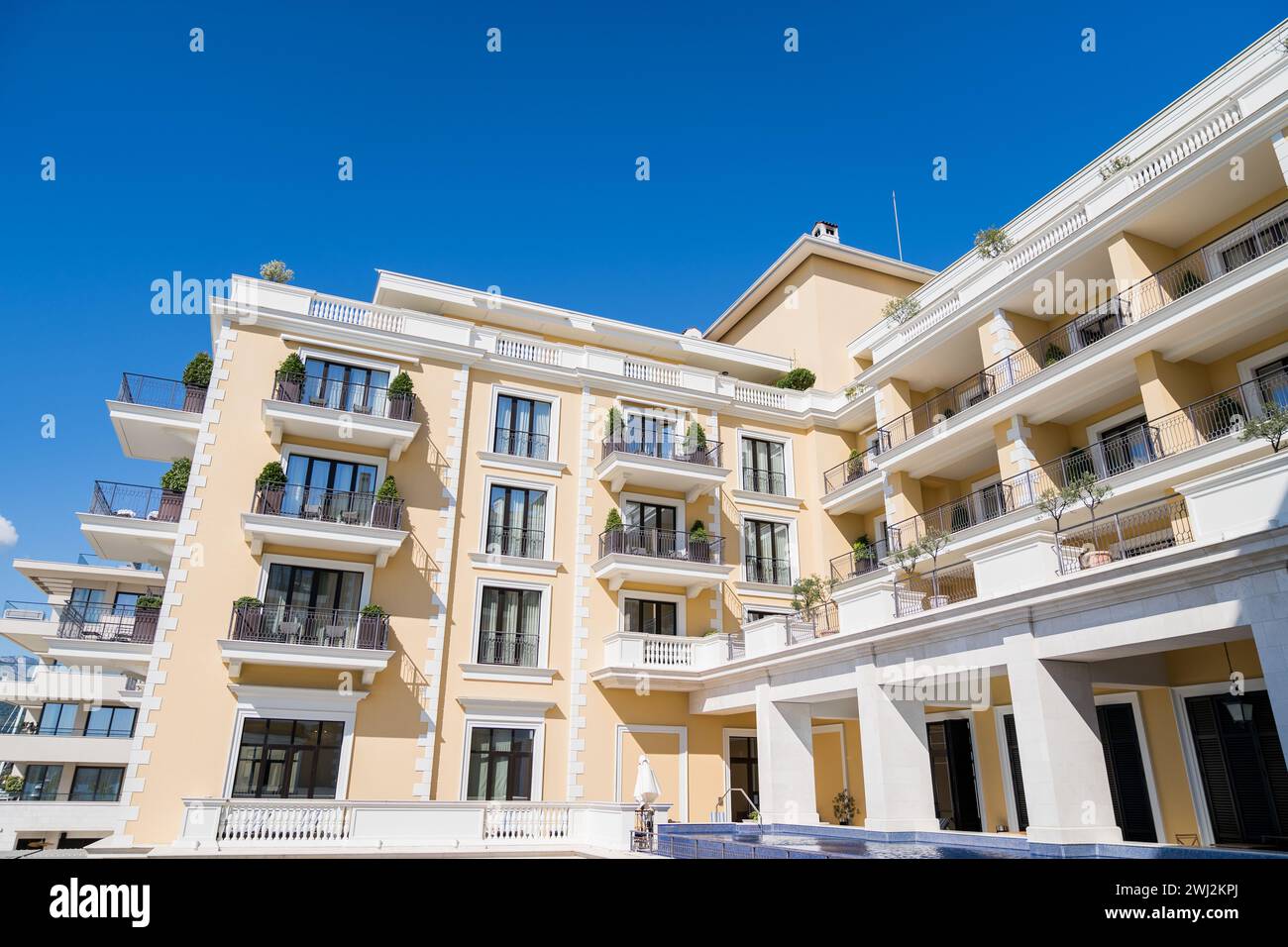 Gelbe Fassade des Regent Hotels mit Terrassen vor dem blauen Himmel. Porto, Montenegro Stockfoto