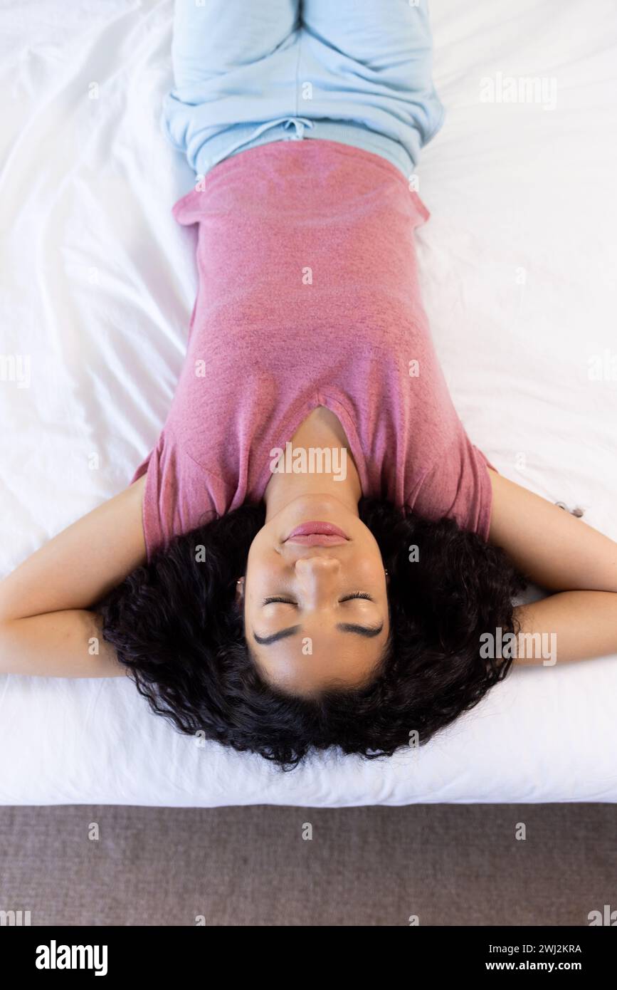 Birassische Frau schläft im Bett in sonnigem Haus Stockfoto