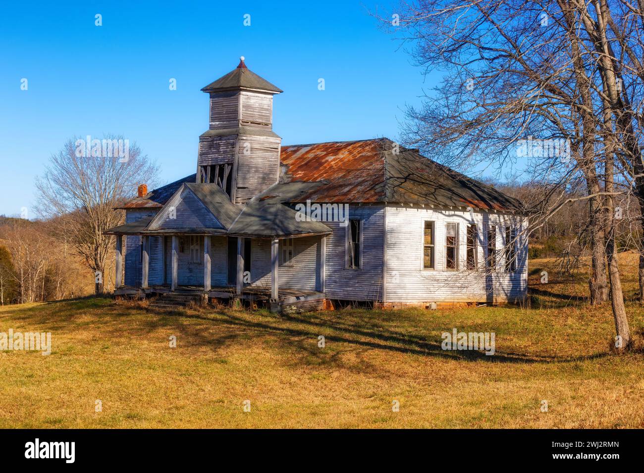 Verlassenes altes Schulhaus liegt auf einem verrotteten Feld. Stockfoto