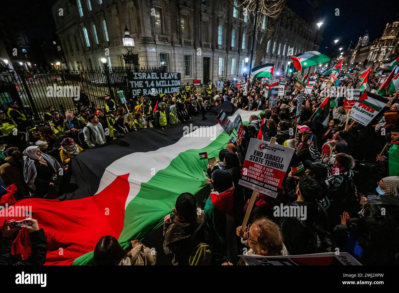 London, Großbritannien. Februar 2024. Die Menge breitet sich rasch aus und überquert schließlich die Straße zur Downing Street, wo eine große palästinensische Flagge zu Gesängen des freien palästinas aufgerollt wird - in letzter Minute Protest gegen den israelischen Angriff auf Rafa in Gaza und allgemein für eine Waffenruhe in Palästina jetzt. Guy Bell/Alamy Live News Stockfoto