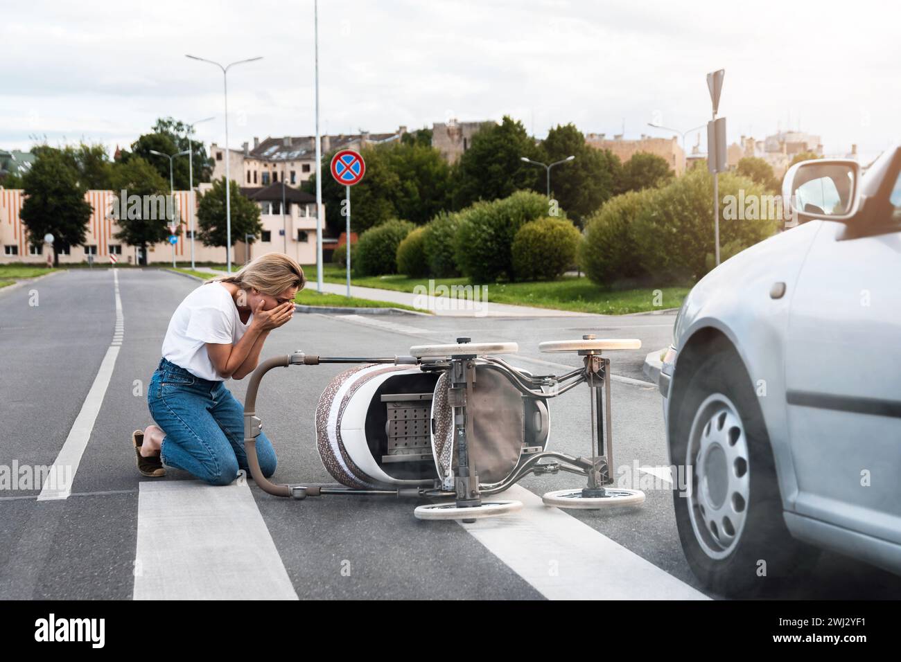 Entsetzliche Mutter auf dem Weg nach einem Autounfall, als ein Fahrzeug ihren Kinderwagen trifft. Stockfoto