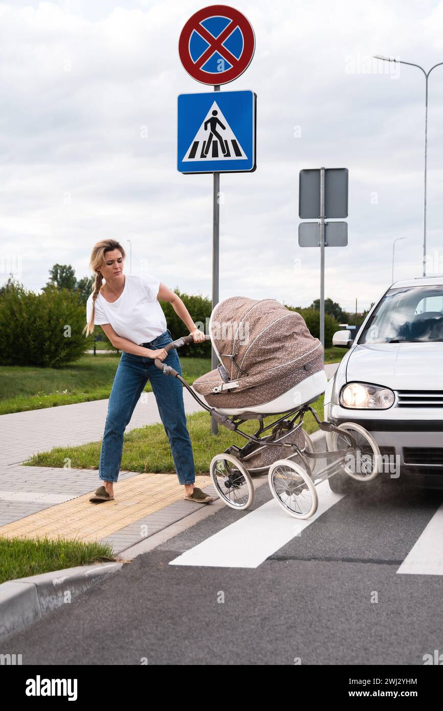 Mutter auf dem Fußweg nach einem Autounfall, als das Fahrzeug ihren Kinderwagen trifft Stockfoto