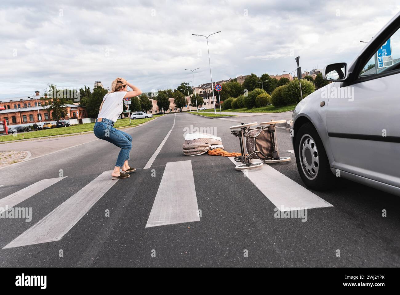 Schockierte Mutter auf dem Gehweg nach einem Autounfall, als das Fahrzeug ihren Kinderwagen traf Stockfoto