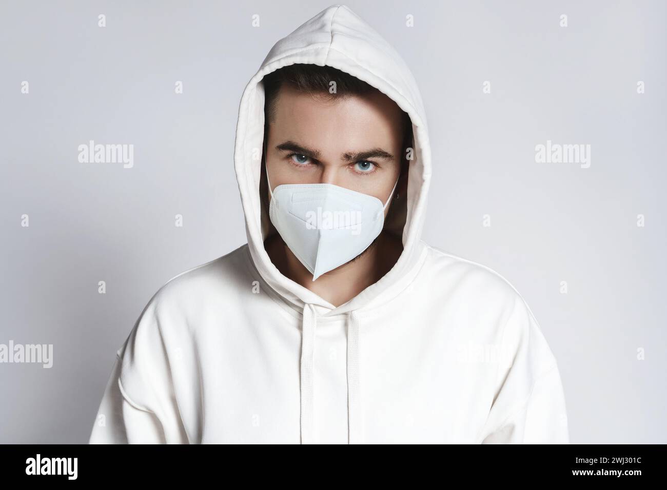 Junger Mann mit weißem Hoodie und ffp2-Atemschutzmaske Stockfoto