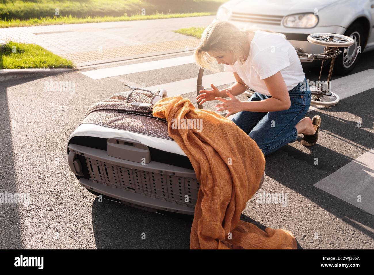 Schockierte Mutter auf dem Gehweg nach einem Autounfall, als ein Fahrzeug ihren Kinderwagen trifft. Stockfoto
