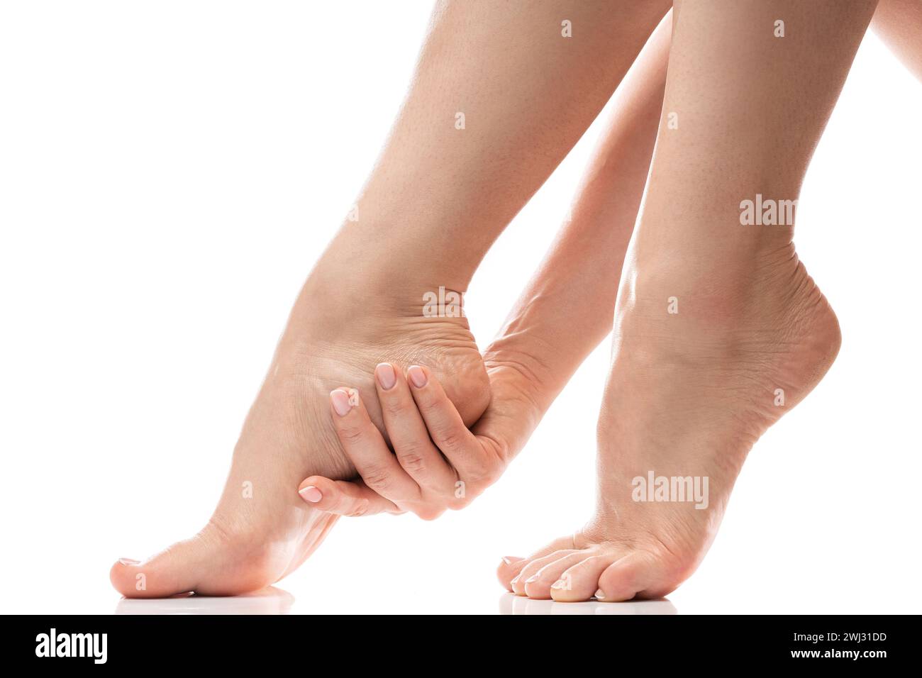Frau, die sanft die weiche Haut ihrer Ferse berührt. Weibliche Füße auf weißem Hintergrund. Stockfoto