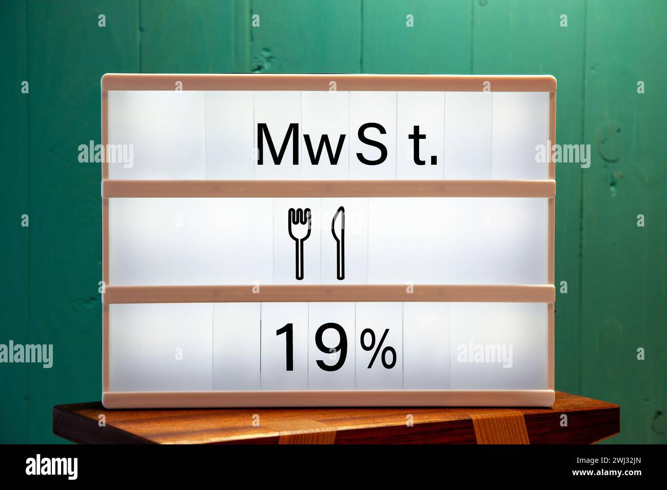 19 % Nachricht auf weißem Schild zu Hause auf einem grünen Regal. Erhöhung der Mehrwertsteuer in der Gastronomie. Stockfoto