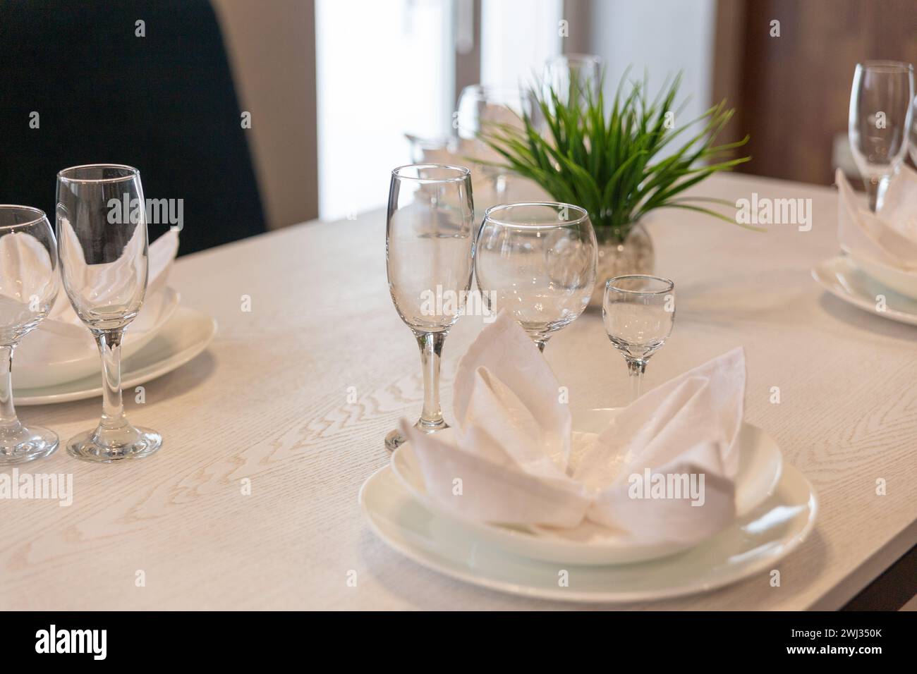 Gläser, Teller, Servietten werden zum Abendessen in einem Restaurant mit gemütlicher Einrichtung serviert. Gläser und Teller auf einem Tisch im Restaurant serviert zum Abendessen. Stockfoto