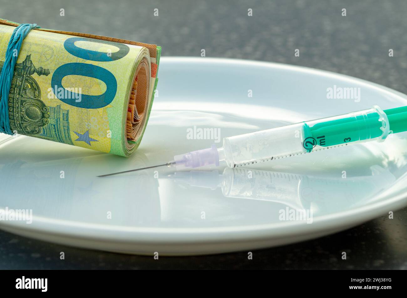 100- und 50-Euro-Scheine, die mit einem Gummiband verbunden sind. Spritze Und Eurogeld Auf Weißer Platte. Arzneimittelsucht Stockfoto