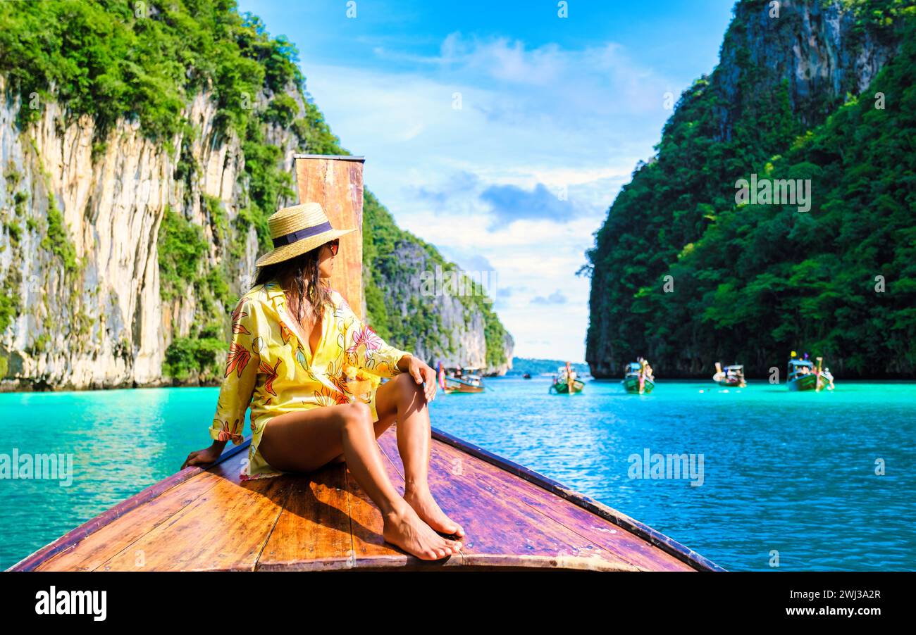 Asiatische Frauen vor einem Longtail-Boot in Kho Phi Phi Thailand in der Pileh Lagune mit türkisfarbenem Wasser Stockfoto