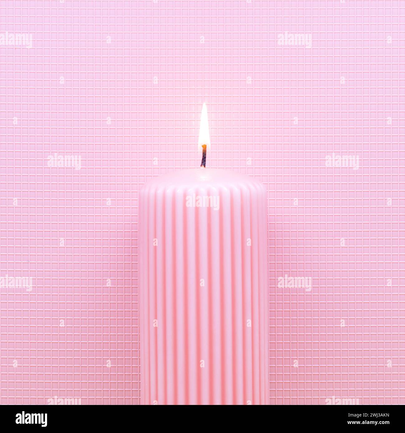 Abstrakte brennende Kerze auf rosa Hintergrund. Minimal flach Lay Weihnachten oder Geburtstag Thema. Neues Jahr Stockfoto