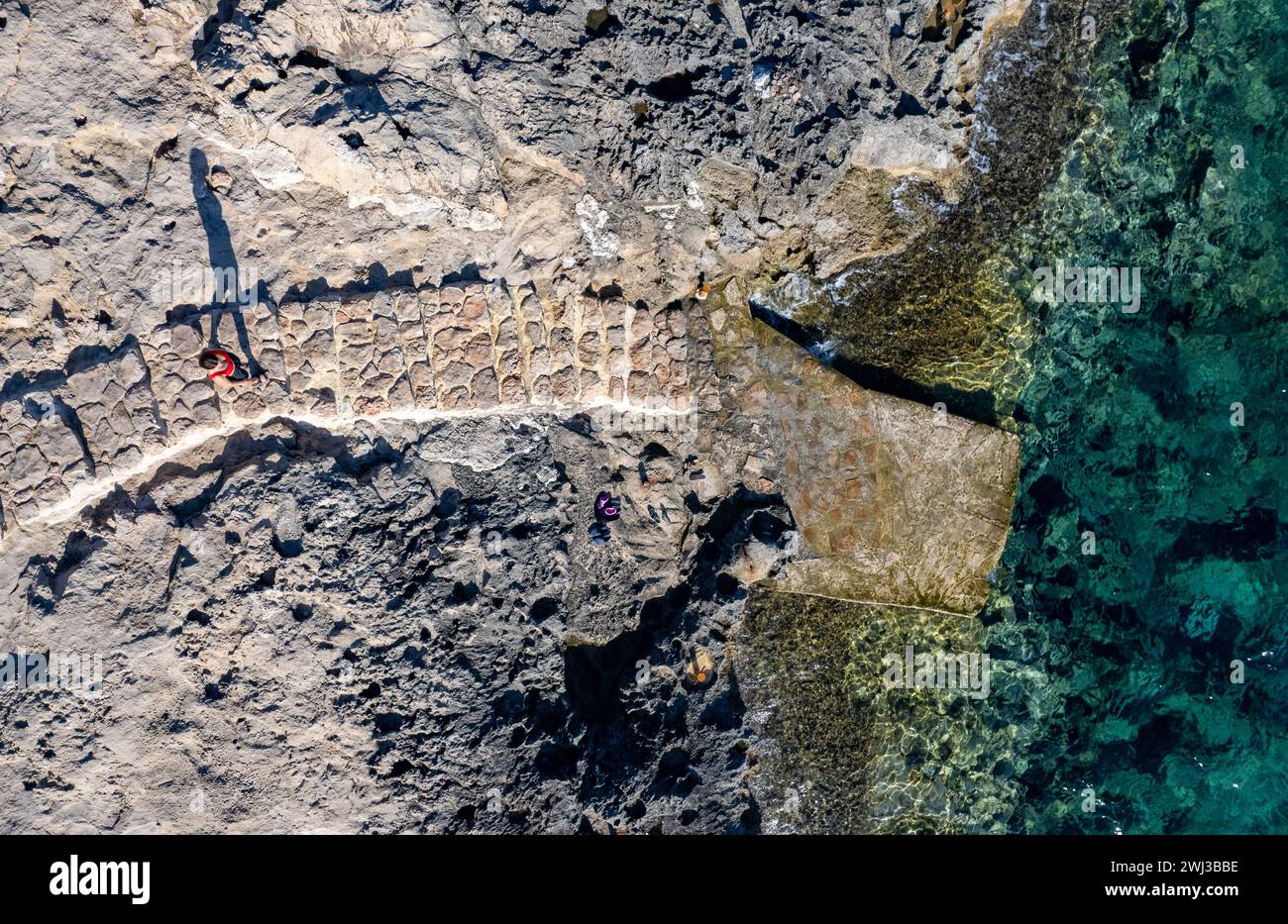 Ich hatte einen Blick auf unbekannte Leute, die an einem felsigen Strand spazieren gingen. Idyllisches, ruhiges Meer Stockfoto