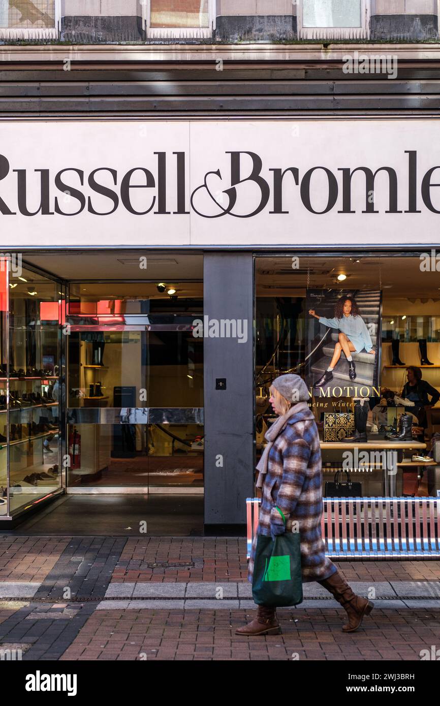 Kingston-upon-Thames, London UK, 12. Februar 2024, Frau, die an einer High Street Filiale von Russell und Bromley High End Shoe Shop Retail Outlet vorbeiläuft Stockfoto