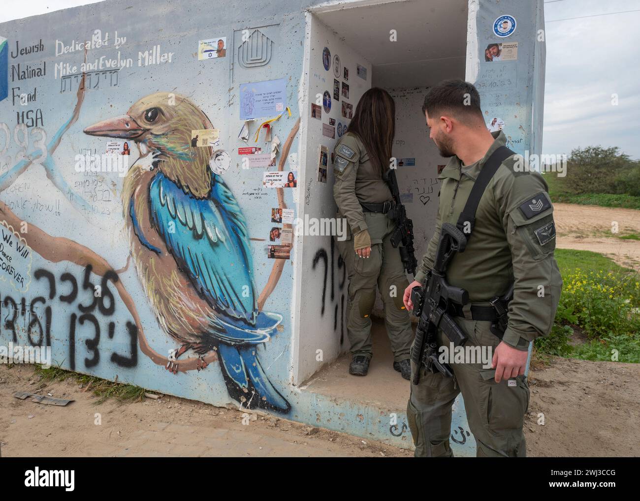 Ein israelischer Soldat schaut am 12. Februar 2024 auf eine abgebaute Bushaltestelle auf der Amainstraße in der Nähe israelischer Gemeinden. Am 7. Oktober 2023 versammelten sich 20 Israelis in diesem geschützten Schutzhaus, als sie vor der Tanzparty Re'im, Israel, in der die Hamas-Terroristen israelische Parteigänger ermorden, flohen. Ein israelischer Soldat, Aner Shapira, betrat das Schutzhaus und sagte den Menschen darin, ruhig zu sein, dass er die Kontrolle übernehmen würde. Hamas-Terroristen begannen, Handgranaten in den Unterschlupf zu werfen, und Anna warf sie mehrmals nach draußen zurück und rettete einige darin, bis Aner selbst unter der Handgranate getötet wurde Stockfoto