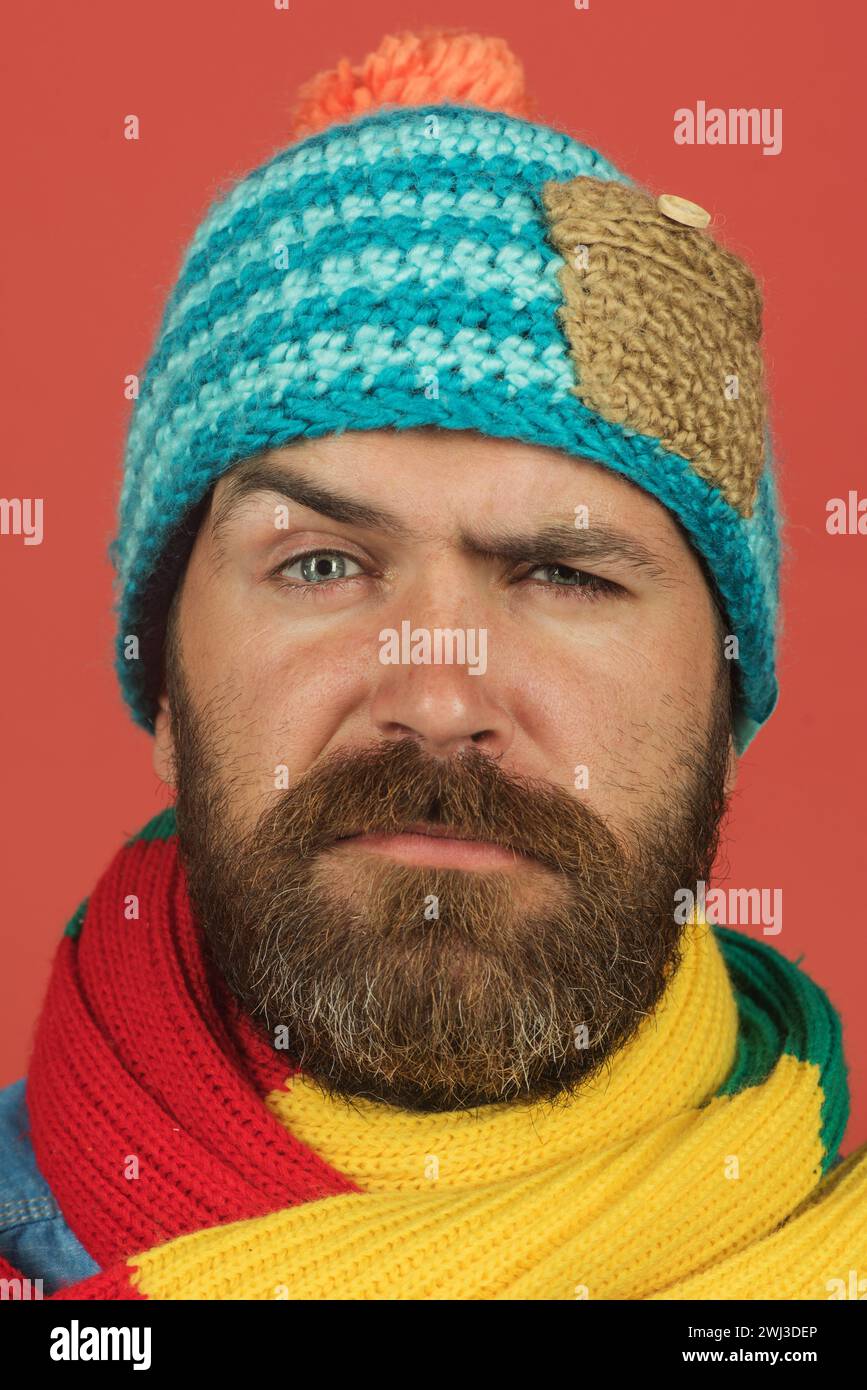 Porträt eines ernsthaften bärtigen Mannes in buntem Schal und Wollmütze. Lässiger Look. Modischer Mann in Winterkleidung. Herren Herbst-Winter-Mode. Gut Aussehend Stockfoto