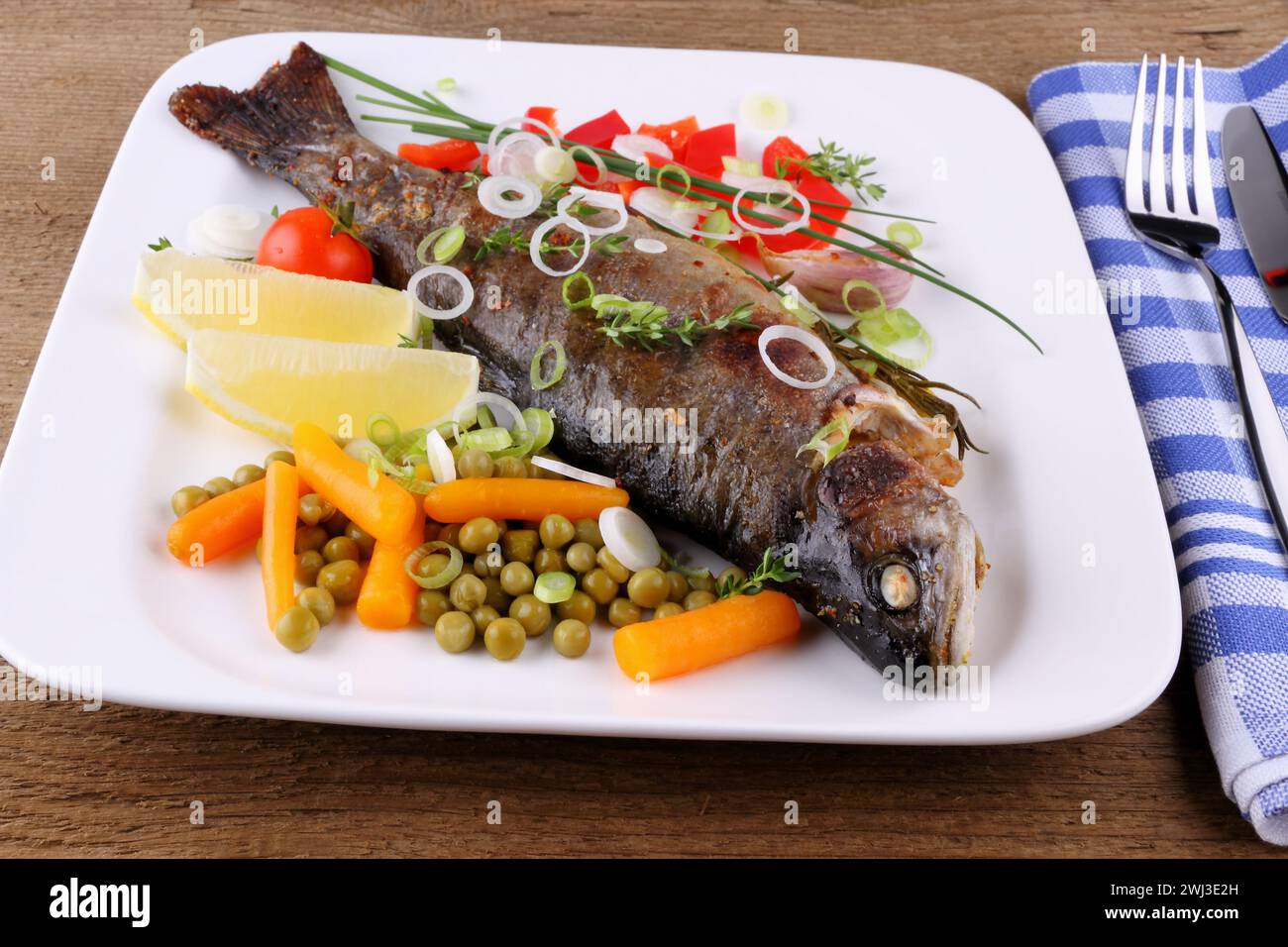 Gegrillte Forelle mit ganz anderem Gemüse mit Besteck Stockfoto