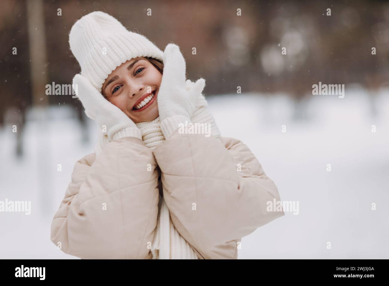 Glücklich lächelnde junge Frau Porträt gekleidete Mantel Schal Hut und Fäustlinge genießt das Winterwetter im verschneiten Winterpark. Stockfoto