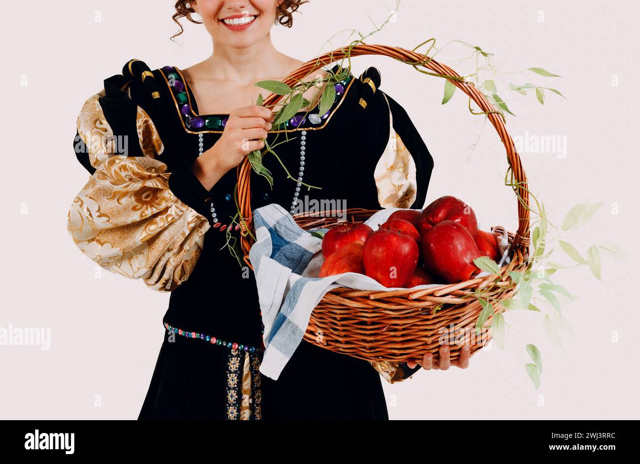 Frau in einem mittelalterlichen Kleid gekleidet, mit einem Korb mit Äpfeln isoliert weißem Hintergrund. Stockfoto