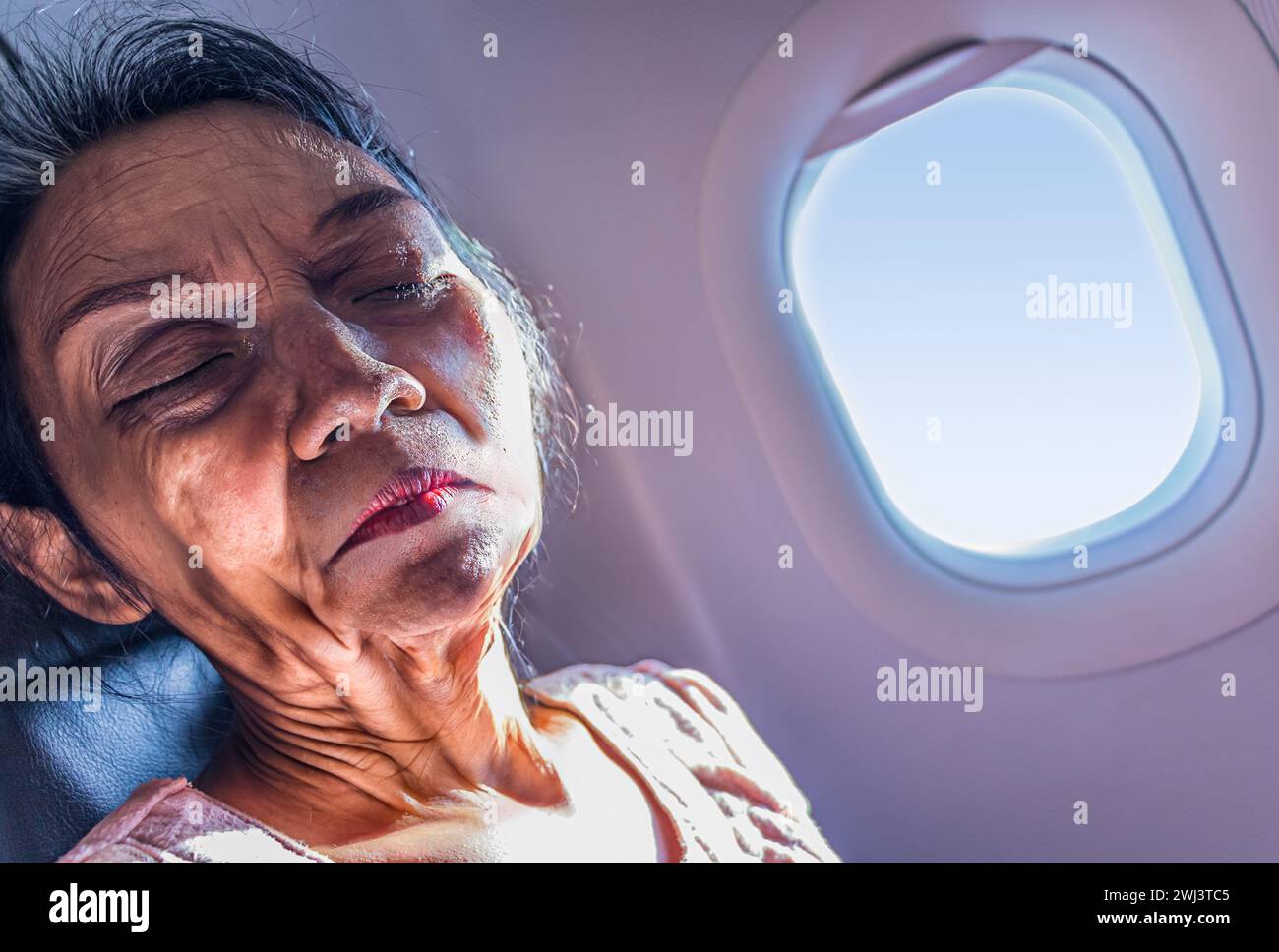 Porträt einer alten Frau, die in einem Flugzeug am Fenster sitzt Stockfoto