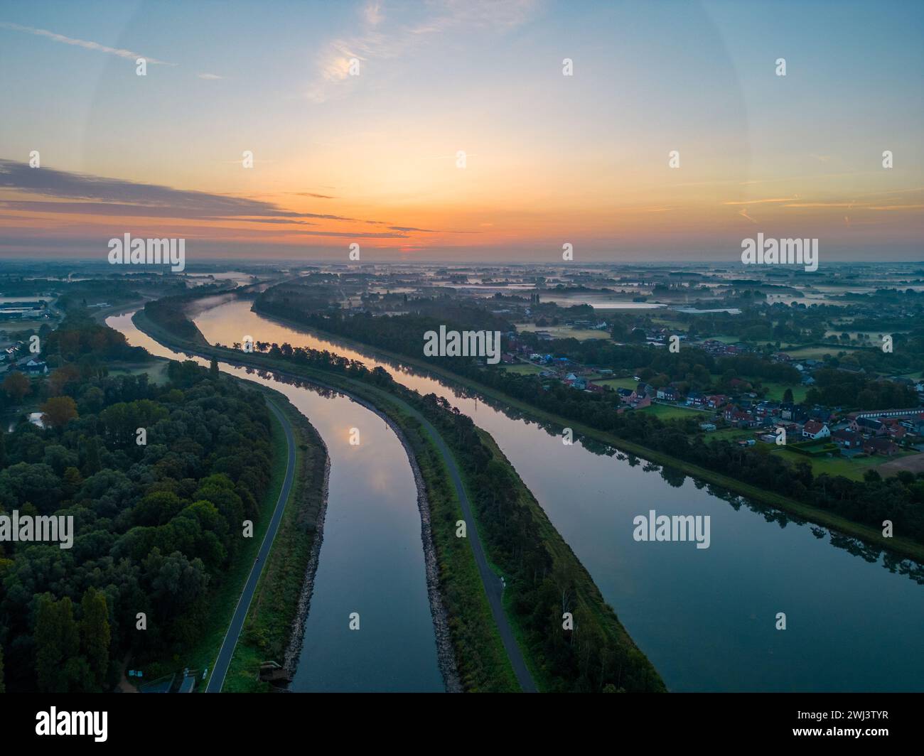 Abenddämmerung über dem Fluss: Blick auf einen Wasserweg bei Sonnenuntergang aus der Vogelperspektive Stockfoto