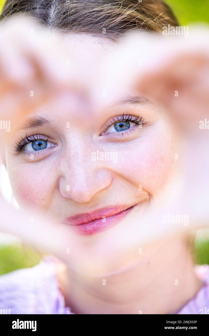Eine Frau, die ihr Gesicht mit einer Herzform umrahmt Stockfoto
