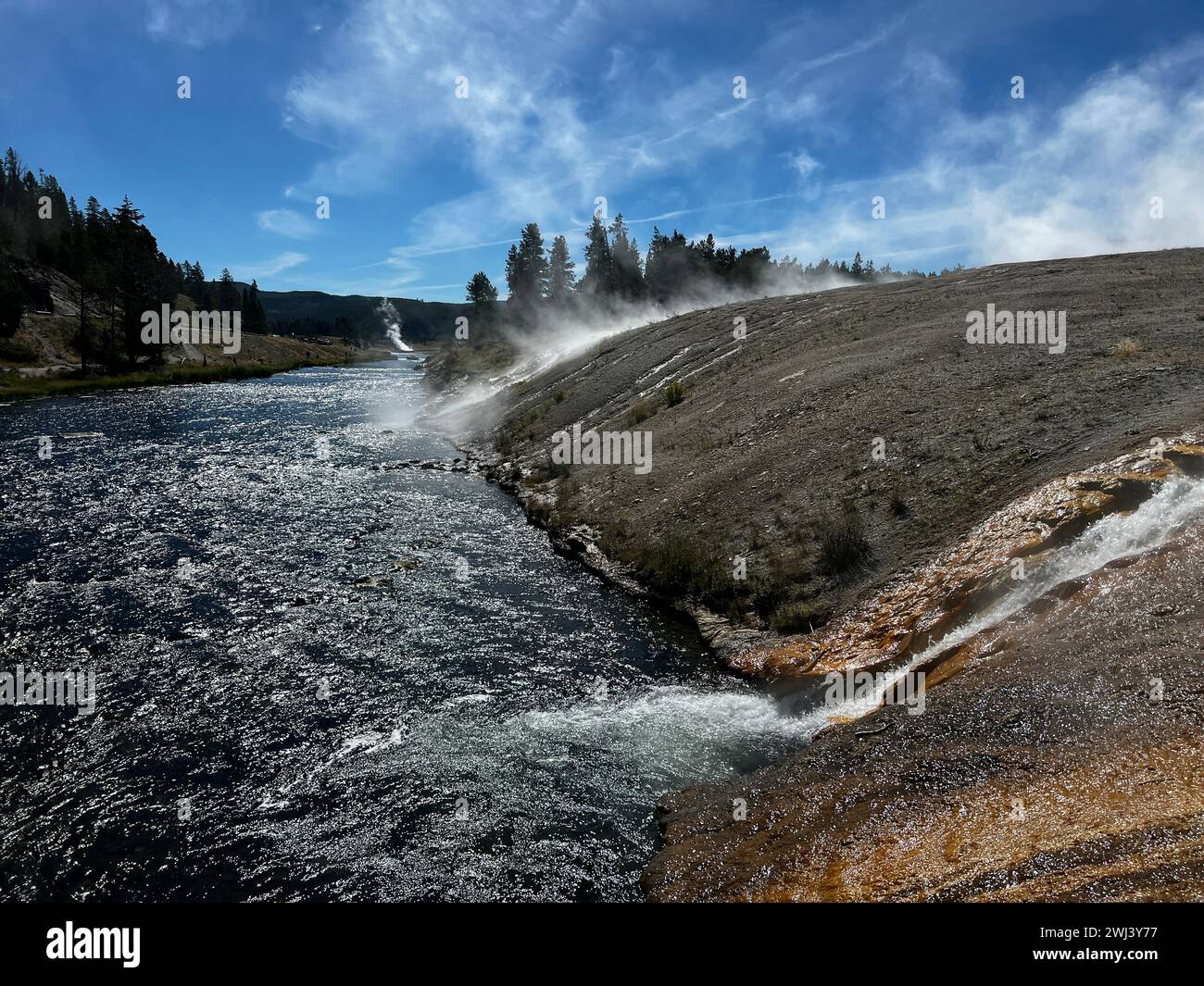 Ein ruhiger Bach schlängelt sich durch eine üppige, bewaldete Berglandschaft und das Flussufer von Prismatic Springs Stockfoto