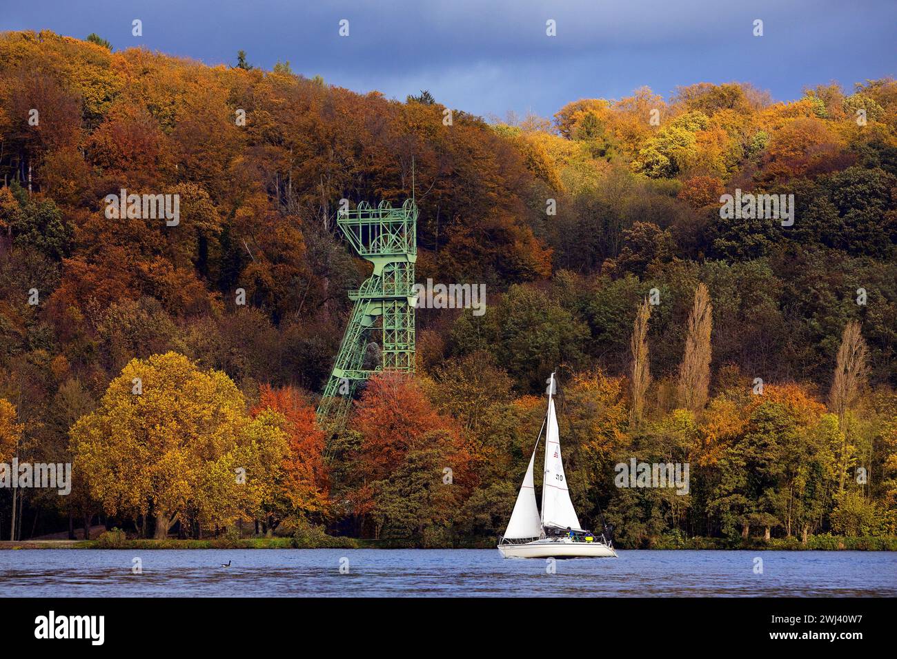 Ein Segelboot im Herbst mit der Förderstruktur der Zeche Carl Funke, Baldeneysee, Essen Stockfoto