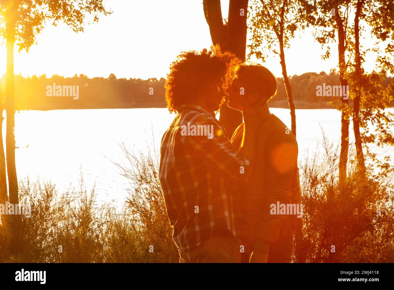 Goldene Stunde Umarmung: Liebe beleuchtet durch Sonnenuntergang Stockfoto