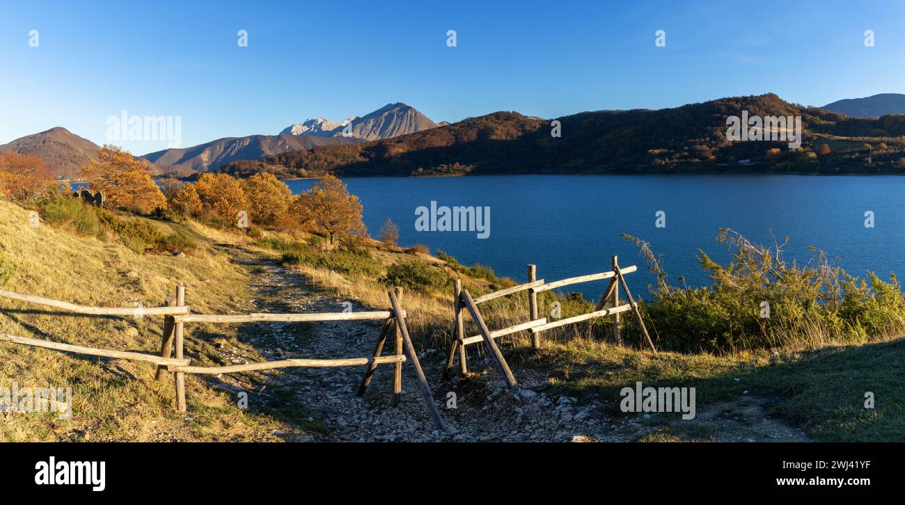 Holzzaun und Wanderweg am Ufer des Campotosto-Sees in den Bergen der Abruzzen in Italien Stockfoto
