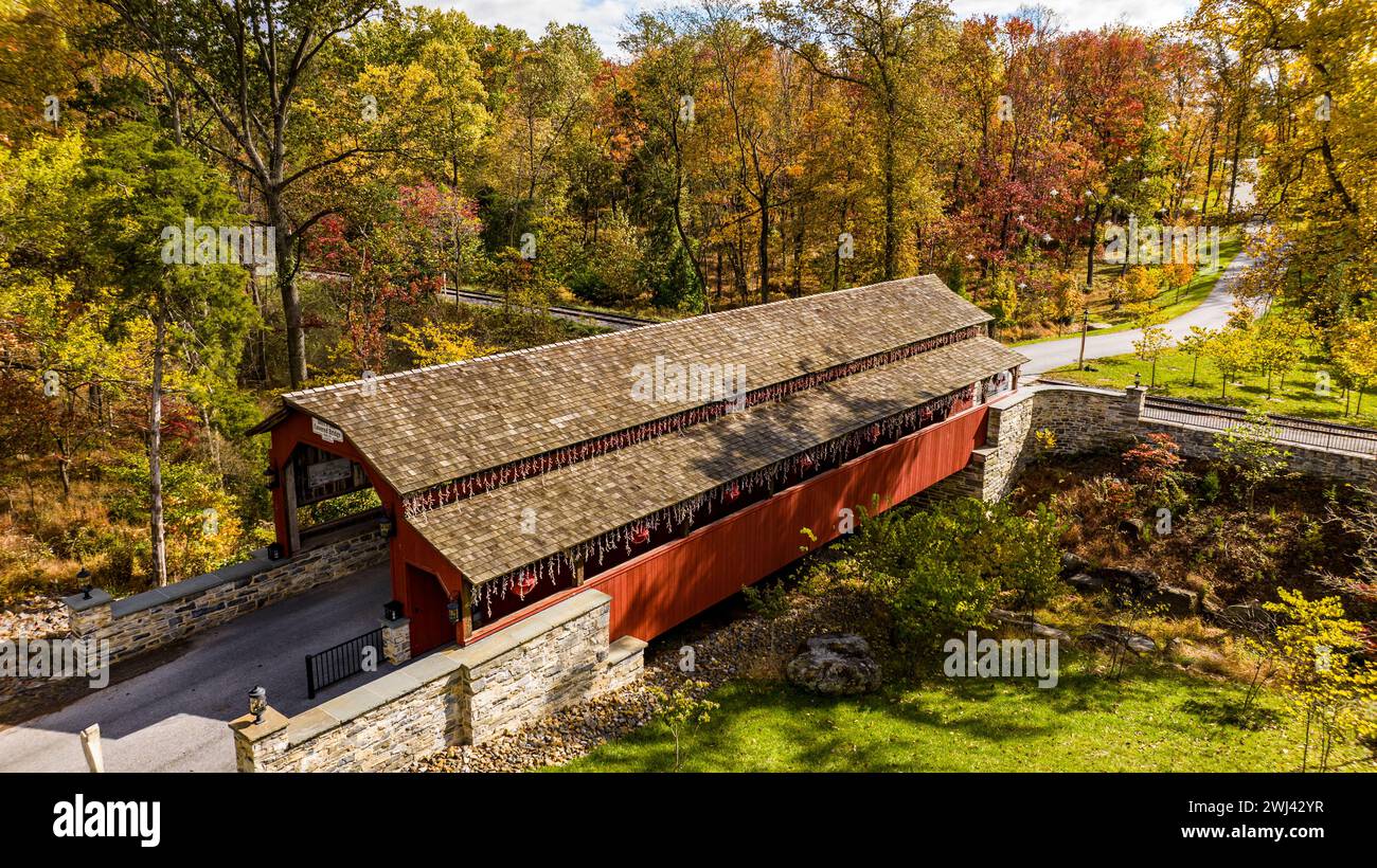 Aus der Vogelperspektive auf eine überdachte Brücke mit einem Grar Truss, die an einem Herbsttag einen Bach überquert Stockfoto