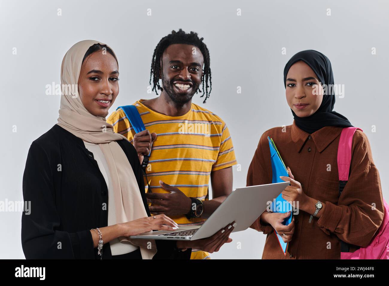 Eine Gruppe von Studenten, darunter eine afroamerikanische Studentin und zwei Hijab-tragende Frauen, stehen vereint gegen eine unberührte weiße Ba Stockfoto