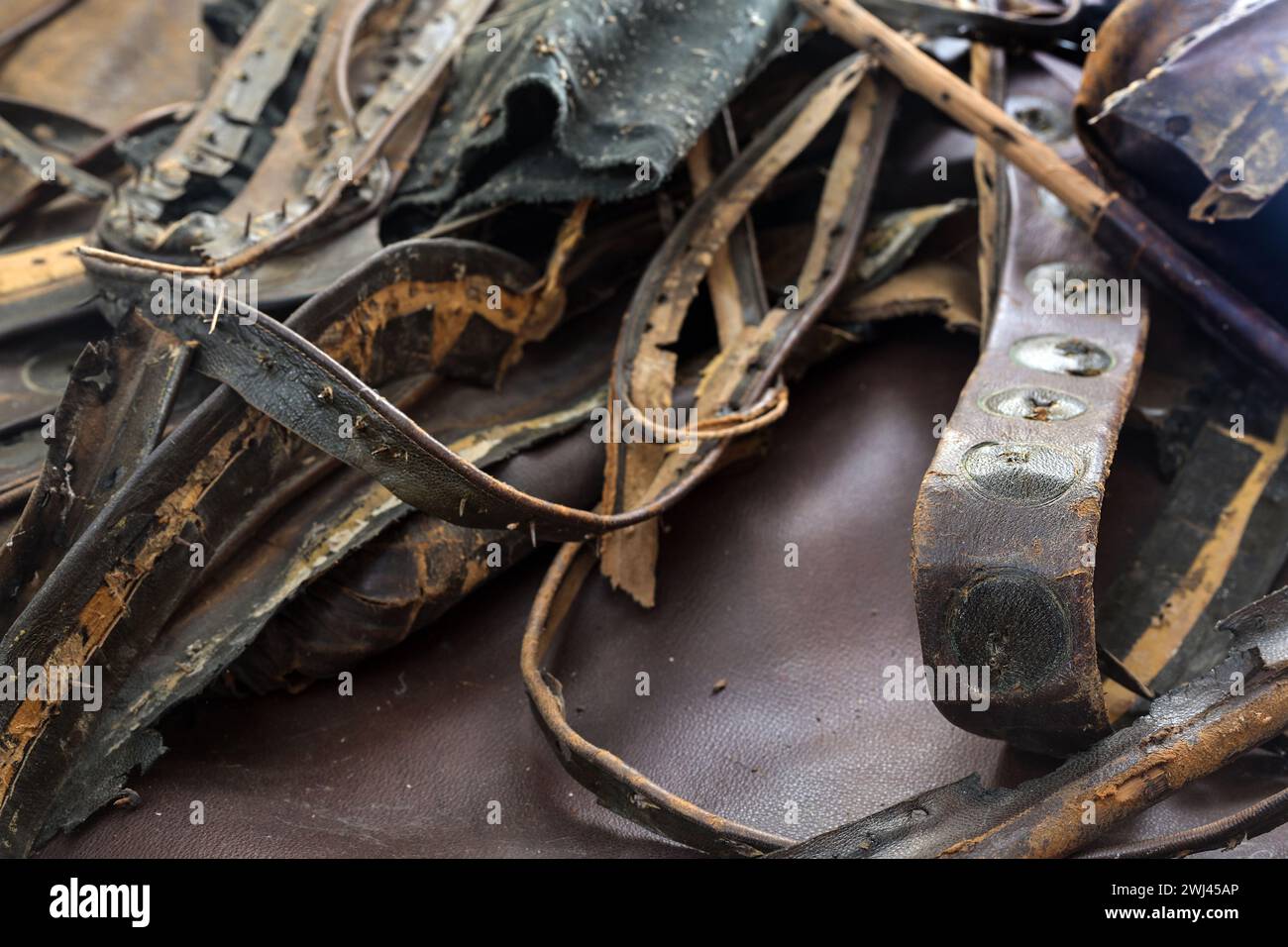 Dunkelbraune Lederstücke aus einem alten Sitzpolster, gesammelt zum Recycling in einer Handwerkstatt, Kopierraum, ausgewählter Fokus Stockfoto
