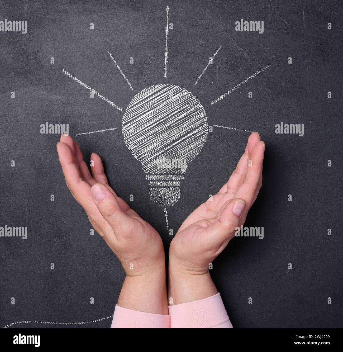 Zwei Handflächen und eine Kreide gezeichnete Glühbirne repräsentieren das Konzept der Suche nach neuen Lösungen Stockfoto