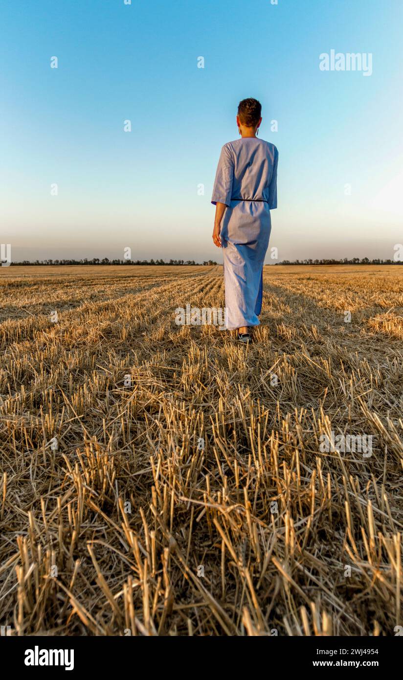 Eine Farmerin geht durch ein gemähtes Weizenfeld in der Ukraine Stockfoto