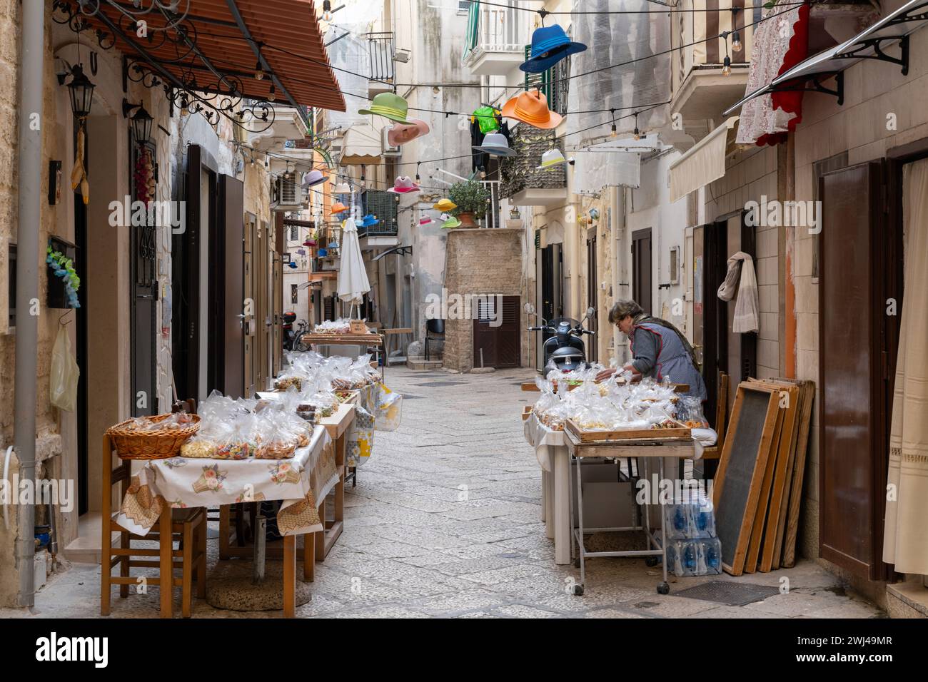 Die legendäre Strada Arco Basso in der historischen Altstadt von Bari Vecchio mit einer Frau, die frische Pasta zum Verkauf in der Straße serviert Stockfoto