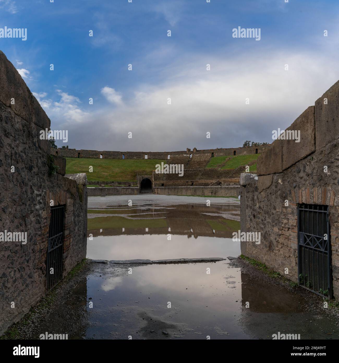 Blick auf das Amphitheater und den Eingang mit Reflexionen in einer Pfütze in der antiken Stadt Pompeji Stockfoto