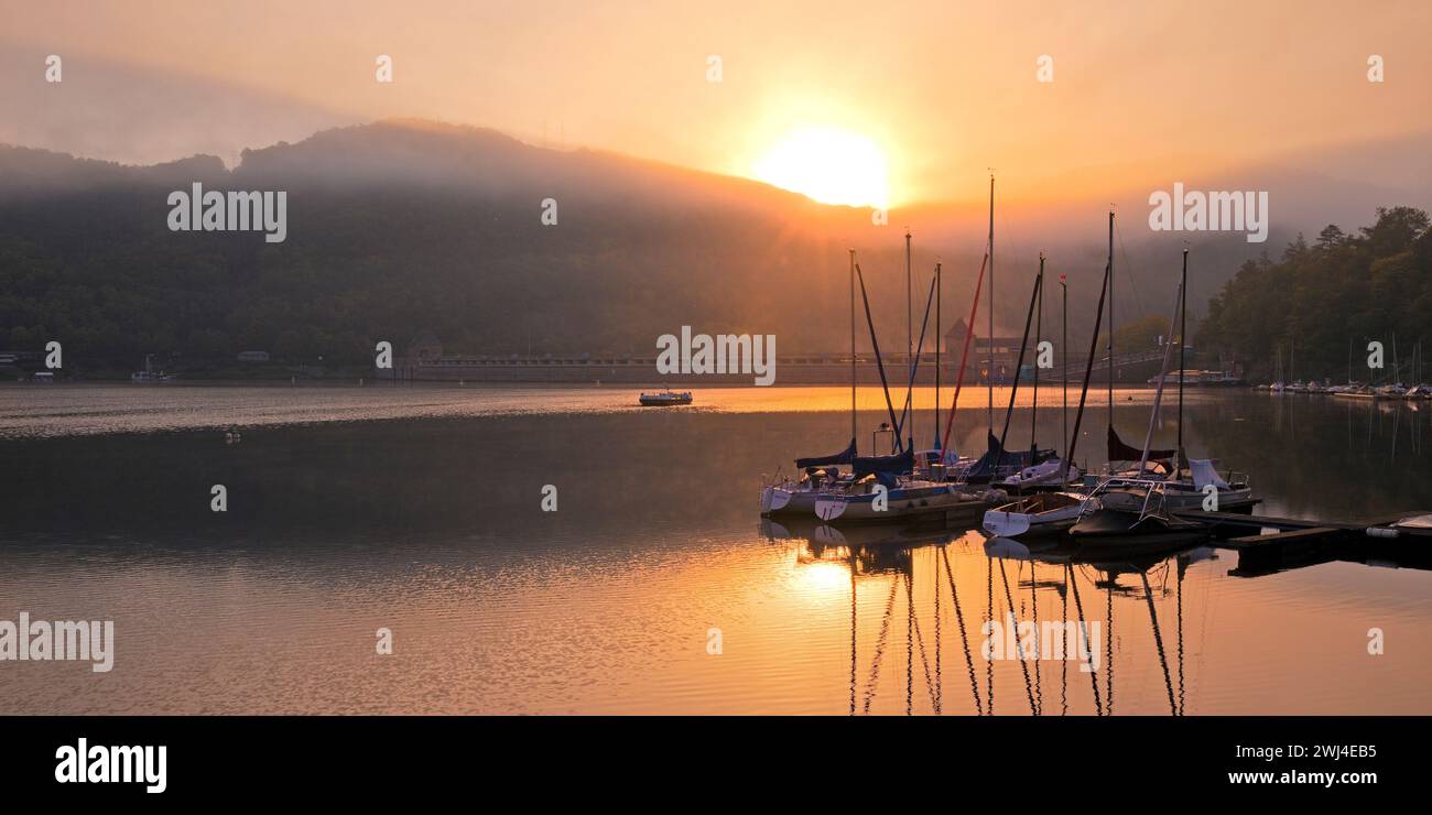 Sonnenaufgang über der Edertalsperre mit Damm und Sportbooten auf dem Edersee, Hessen, Deutschland Europa Stockfoto