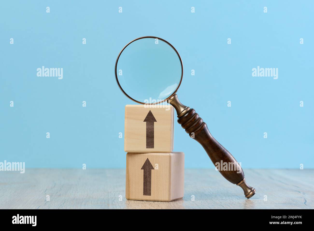 Holzwürfel und Lupe auf blauem Hintergrund Stockfoto