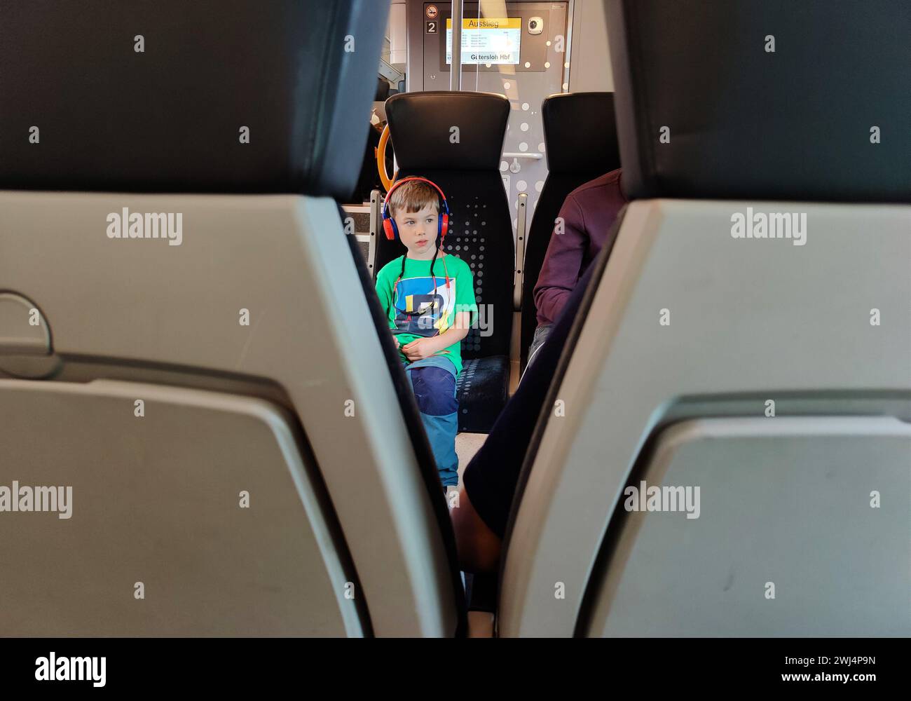 Blick auf einen kleinen Jungen mit Kopfhörern in einem lokalen Zug, der durch Ostwestfalen fährt Stockfoto
